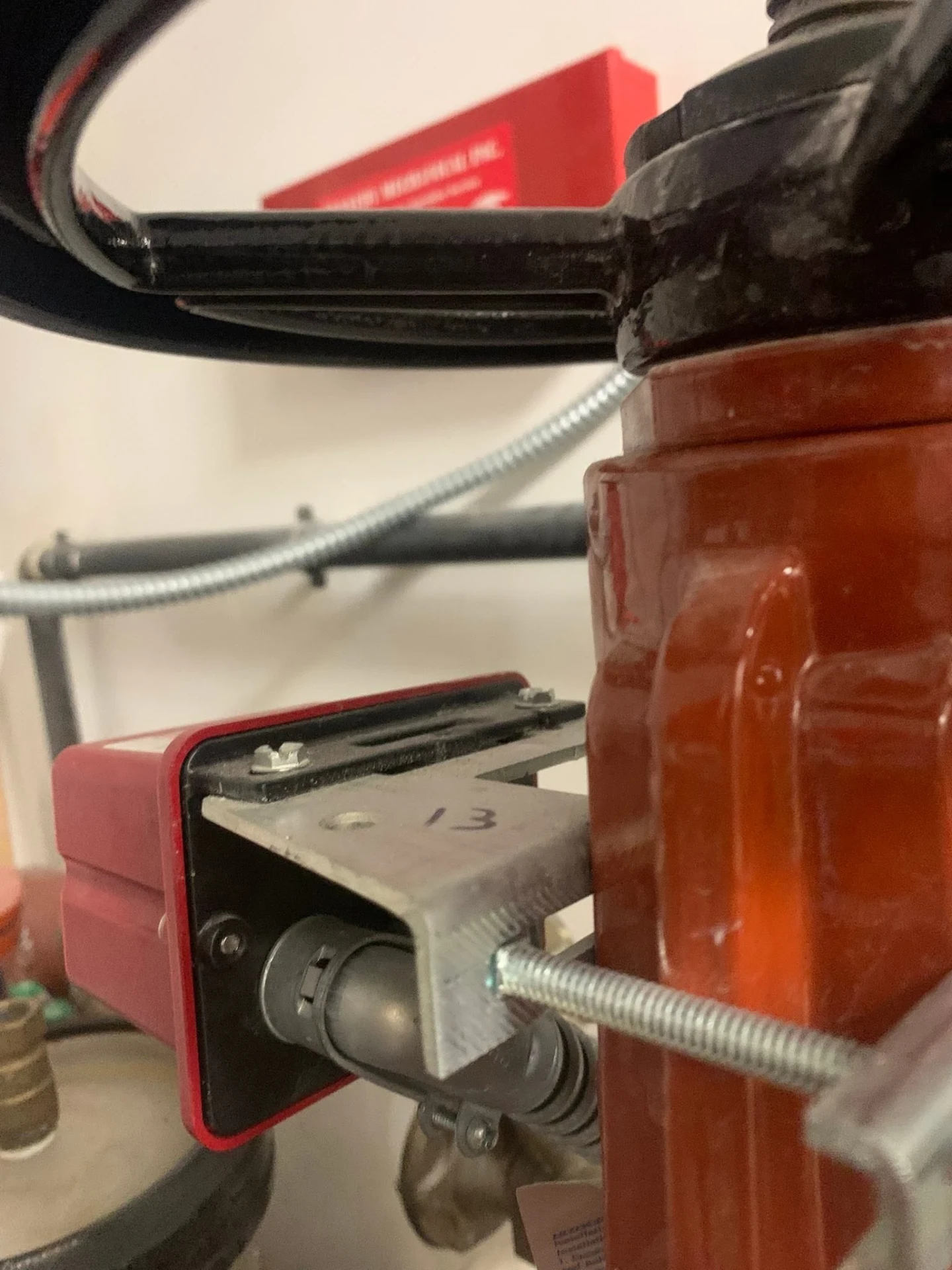 Red tamper switch bracket mounted to an orange grooved fire line valve with conduit running to the housing
