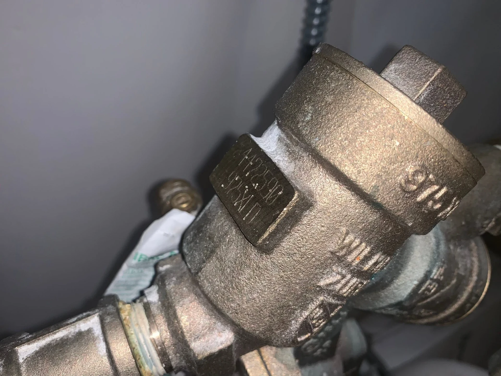 Close up of a brass Wilkins backflow check valve body with threaded fittings on a residential water line