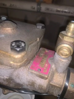 Cast cover plate and pink identification tag on a Watts reduced pressure backflow preventer