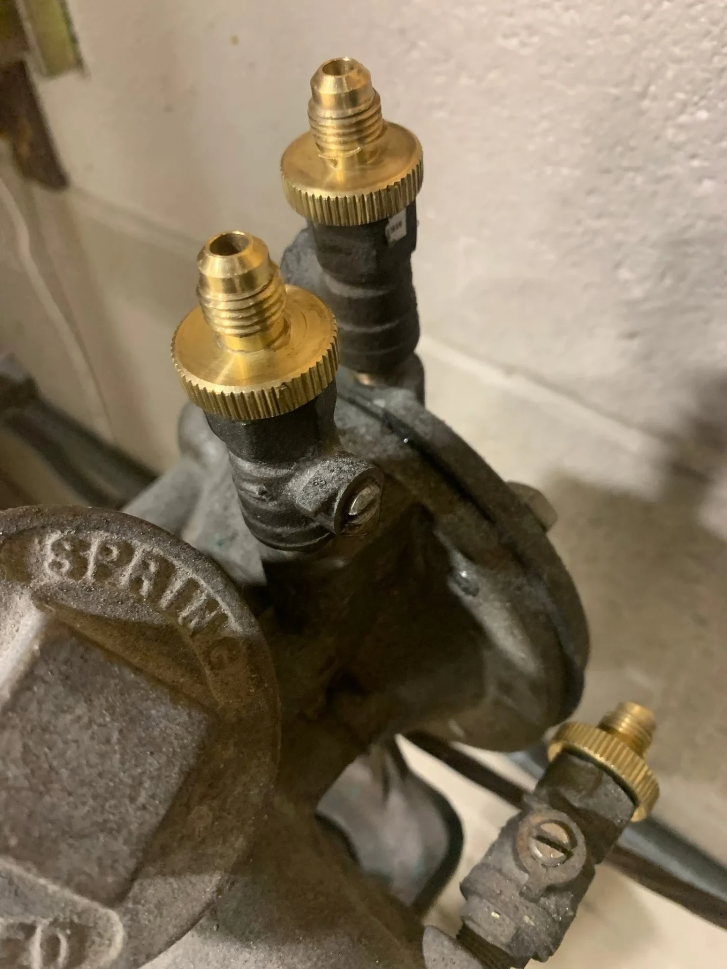 Close up of two brass flare test fittings threaded into a cast iron backflow preventer body